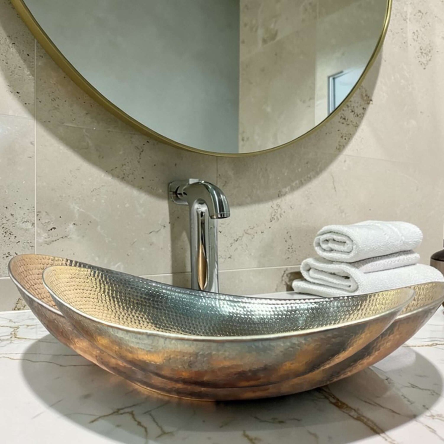 hammered brass bathroom vessel sink displayed with a modern faucet and fluffy towels in an elegant bathroom setting.