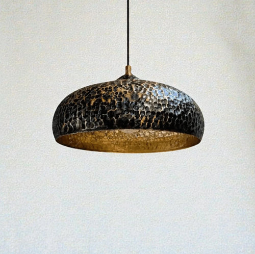 Hammered metal pendant light against a plain background