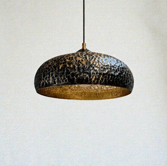 Hammered metal pendant light against a plain background