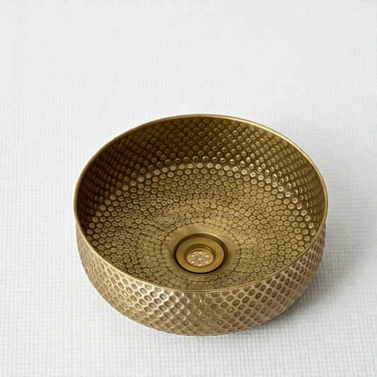 Elegant oxidized copper vessel sink featuring a unique textured design and polished drain.