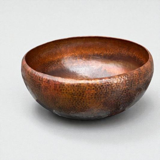 Hammered Brown Copper Vessel Sink displayed on a marble countertop with a lamp and folded towels.